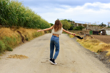 Chica de espalda con los brazos abiertos en campos de trigo. 