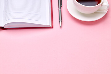 above view for pink desk with diary and tea cup on it. office workplace background backdrop