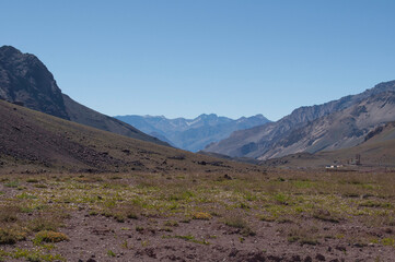 Coordillera de los Andres, paso Argentina Chile, montañas en cielo azul despejado cubiertas por cesped natural. 
