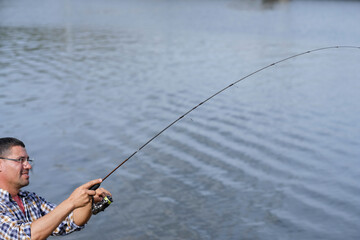 spinning rod in a man's hand. he pulls the catch. Concept of sport, hobby and leisure time.