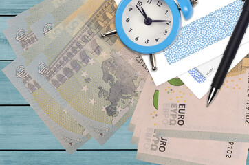 5 euro bills and alarm clock with pen and envelopes. Tax season concept, payment deadline for credit or loan. Financial operations using postal service