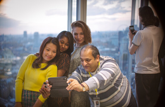 Business people taking selfie at highrise office window
