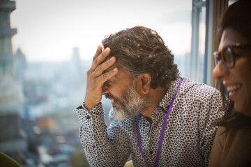 Businessman laughing with head in hands in meeting