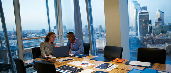 Business people working at laptop in highrise conference room meeting