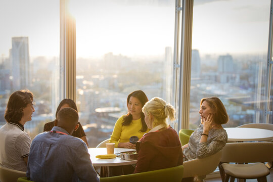 Business people talking in sunny highrise office cafeteria