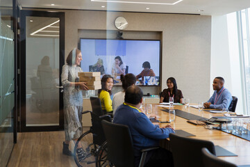 Businesswoman bringing lunch to colleagues in conference room meeting