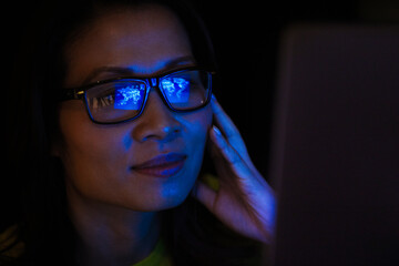 Close up laptop reflection in eyeglasses of businesswoman working late