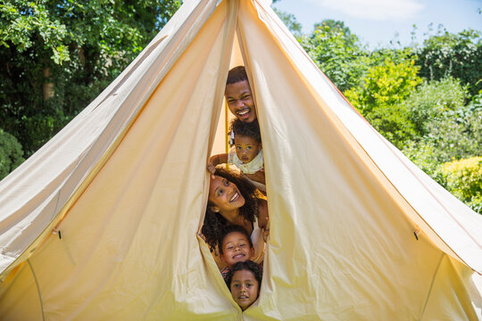 Portrait playful family peering from inside tent