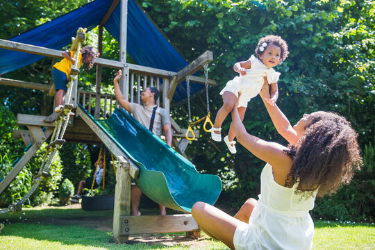 Happy family playing at playground set in sunny summer backyard