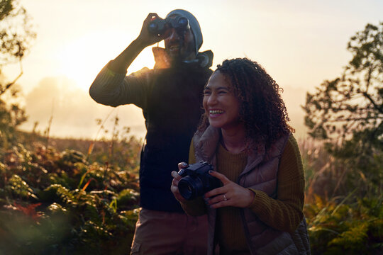 Happy young hiking couple with camera and binoculars in nature