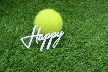 Tennis ball with Happy word for Birthday Greeting is on green grass