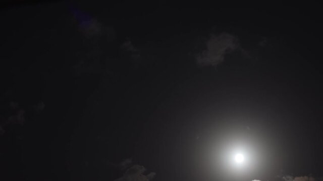 Time-lapse of clouds moving in night sky. Thick clouds cover moon. Moon time lapse, image of big white clouds and stars. 4K quality time lapse video.