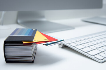 Close view of minimal and clean graphic designer home office workspace with aluminum keyboard, color catalog and computer on white background