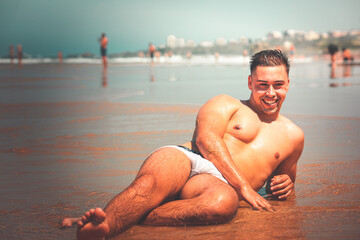 Obraz premium Young caucasian man posing at a beach in a summer morning in the basque coast.