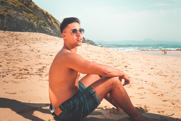 Young caucasian man posing at a beach in a summer morning in the basque coast.