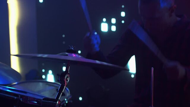 Rock Band Performing at a Concert in a Night Club. Close Up Portrait of a Drummer Playing the Drums. Live Music Party in Front of Bright Colorful Strobing Lights on Stage. 