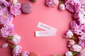  pink fresh fragrance roses  with macaroons and " love you" sign around pink  background. romantic and beauty concept