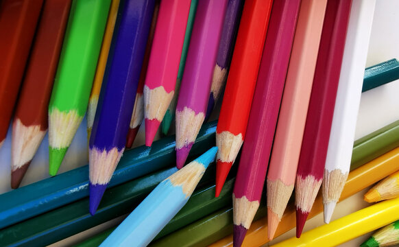 Heap of colored pencils on the white table background