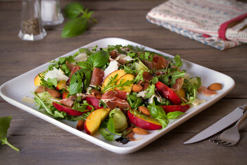 Peach and ham prosciutto salad on white plate. Horizontal photo