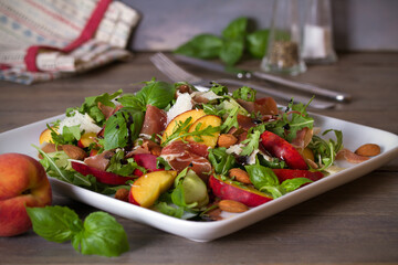 Peach and ham prosciutto salad on white plate. Horizontal photo