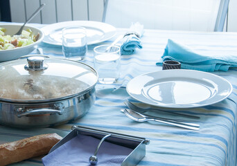 Mesa preparada para comer un menú mediterráneo compuesto por ensalada y un guiso vegetariano....