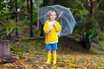 Obraz premium Child playing in autumn rain. Kid with umbrella.