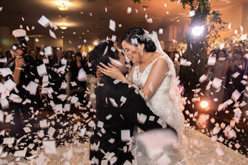 Latino Bride and Groom dancing and celebrating with white confetti flying around them
