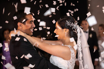 Latino Bride and Groom dancing and looking at each other with white confetti flying around them