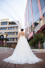 Fototapeta premium Latino Bride elegant open back sleeveless wedding dress with veil moving with wind