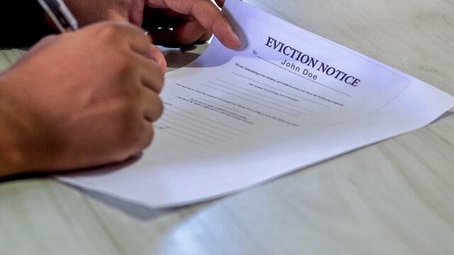 Closeup Asian or African American man signs Eviction Notice