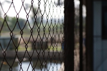 A net made of iron and rhombic wire as a fish pond fence. - Powered by Adobe