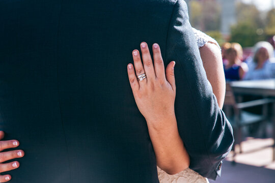 Bride and groom holding each other wedding ring shows