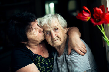 An old woman embrace with her adult daughter.