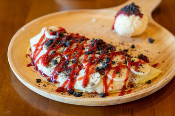 crepe with banana, whipped cream and strawberry sauce