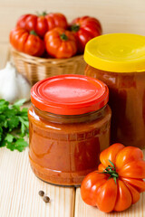 Homemade tomato hot sauce with garlic and pepper in glass jars on wooden table