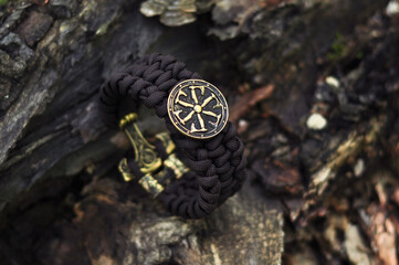 Braided bracelet of brown paracord on the bark of a tree rotifer shield close up