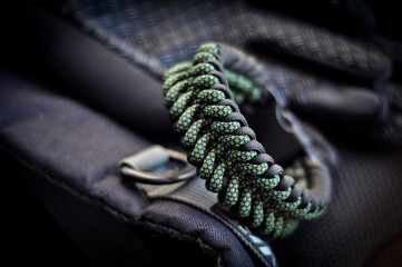 Braided paracord bracelet color camouflage military on hand with lock knot on black backpack