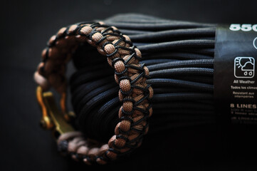 Braided paracord bracelet color brown on the hand with a brass lock on the background of the skein...