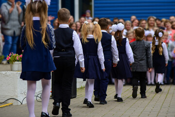 Children first graders walk in a row at school
