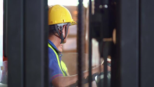 Asian forklift driver in uniform and helmet talk with female manager in warehouse argo