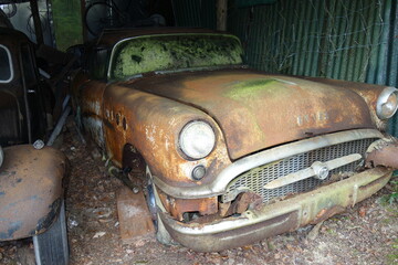 Verrostetes Oldtimer Auto in alter gammeliger Garage . Kaputter mit Rost überzogenes Gefährt . Braun und grün angelaufener Mercedes Benz .