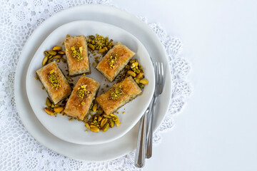 Traditional Turkish Pastry Dessert Baklava special designed on plate with pistachio nuts and cutlery set
