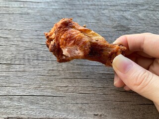 Hand holding fried chicken on a wooden table background