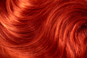 Red hair. Background hair closeup. Female long red-haired close-up as a background. Beautifully laid carroty wavy shiny curls. Hair coloring.Hairdressing procedures. Copy space with space for text.
