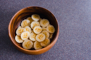 simple food ingredients, sliced banana in wooden bowl as healthy snack