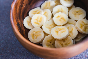 simple food ingredients, sliced banana in wooden bowl as healthy snack