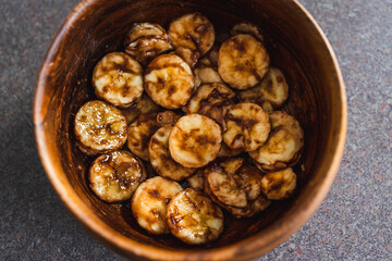 simple food ingredients, sliced banana in wooden bowl with melted cocoa powder coating