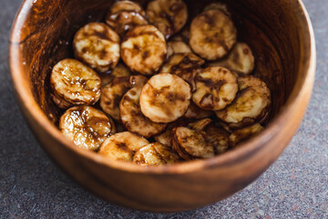 simple food ingredients, sliced banana in wooden bowl with melted cocoa powder coating
