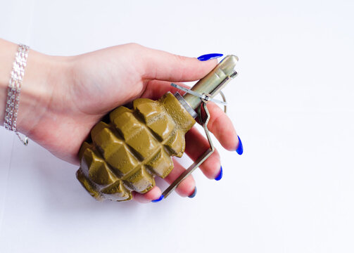 Hand grenade in the hand of a woman on a white background. Explosive ammunition is designed to destroy enemy personnel and equipment using manual throwing. Training smoke grenades in khaki.