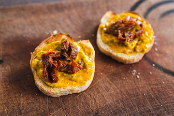 simple food ingredients, bread slices with sweet potoato and kale dip topped with sundried tomatoes